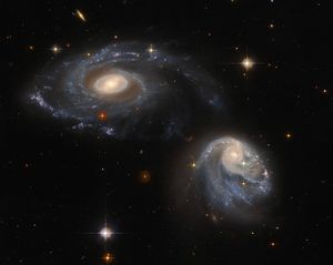 Two spiral galaxies, one at upper-left the other at lower-right, both are nearly face-on providing views of their spiral arms, background stars and galaxies.